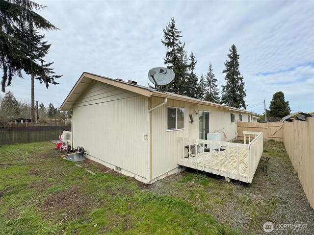 rear view of house with a fenced backyard, a lawn, and a wooden deck