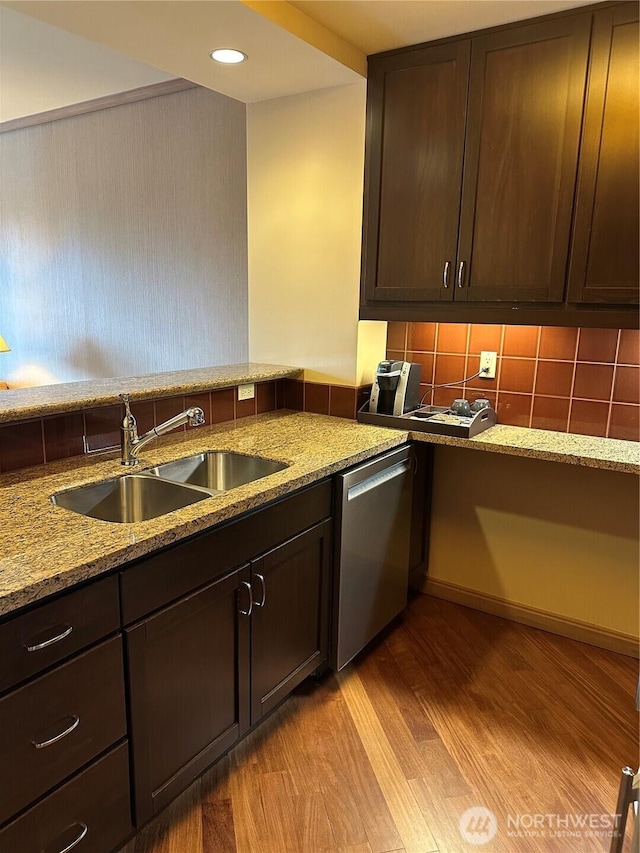 kitchen with dark brown cabinetry, light stone counters, stainless steel dishwasher, light wood-style floors, and a sink