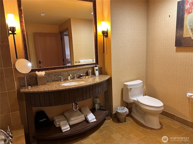 bathroom with toilet, baseboards, and vanity