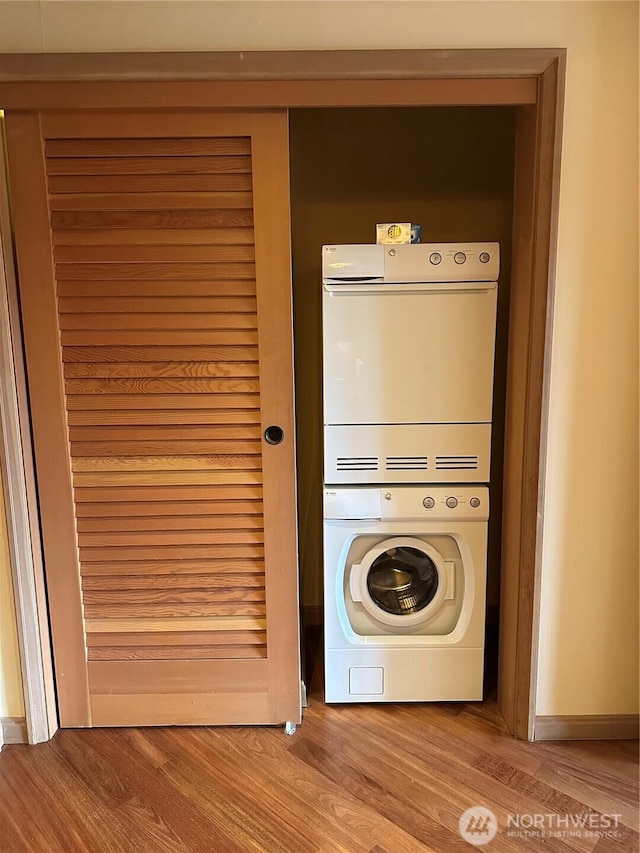 laundry room featuring stacked washer / dryer and wood finished floors