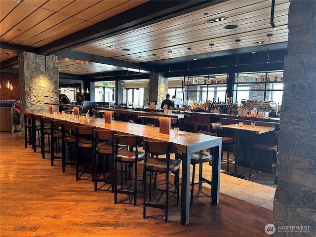 bar with wood ceiling, indoor wet bar, beamed ceiling, and wood finished floors