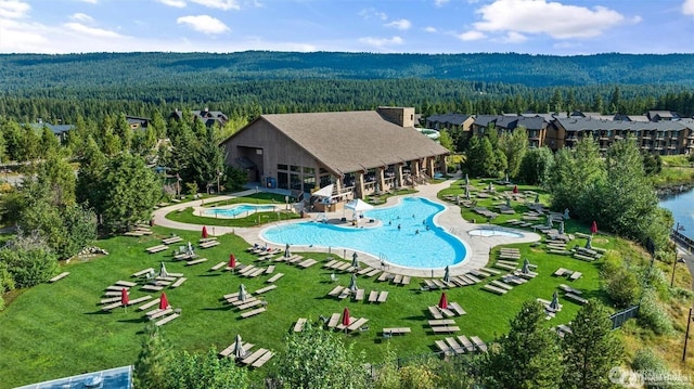 pool featuring a forest view, a yard, and a patio