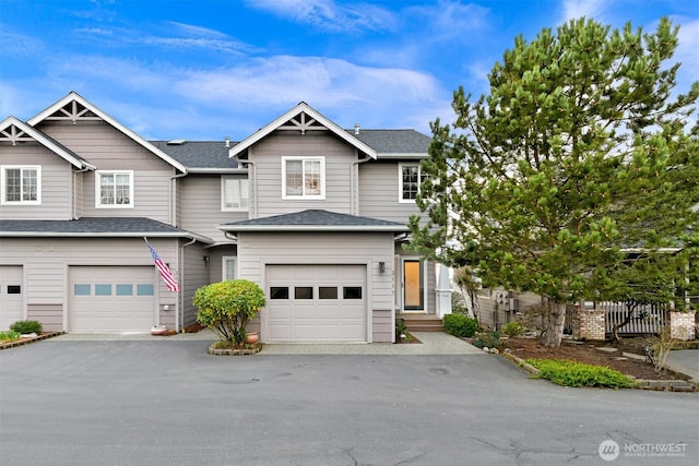 view of front of property with aphalt driveway, an attached garage, fence, and a shingled roof