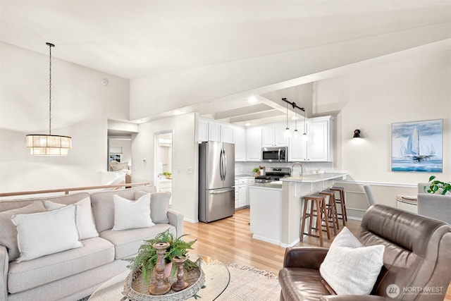 living room featuring lofted ceiling, light wood finished floors, and an inviting chandelier