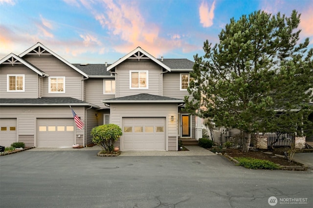 view of front facade with a shingled roof, fence, driveway, and an attached garage