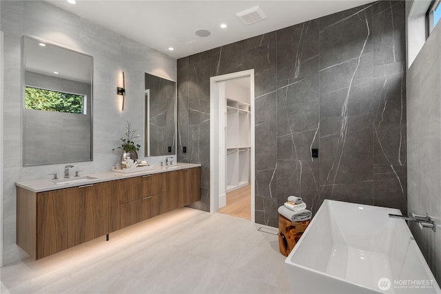 bathroom with a tub, tile walls, and vanity