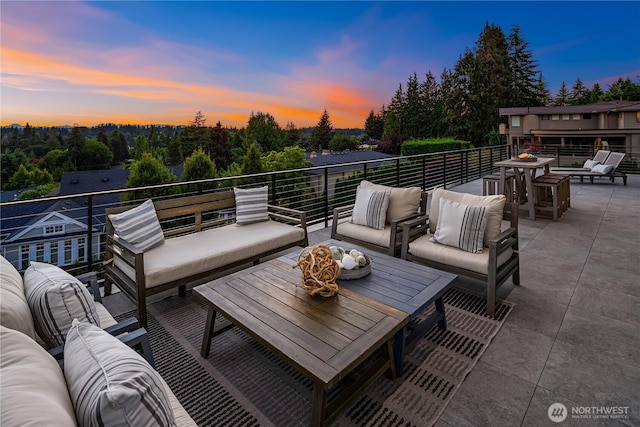 patio terrace at dusk featuring outdoor lounge area and a balcony