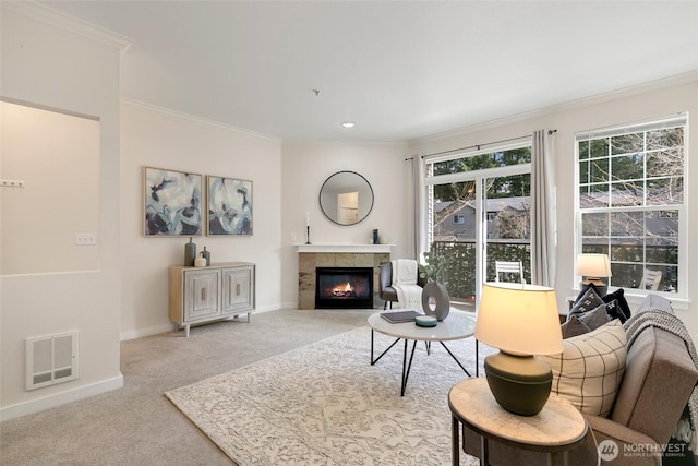 carpeted living room featuring baseboards, a tile fireplace, visible vents, and ornamental molding