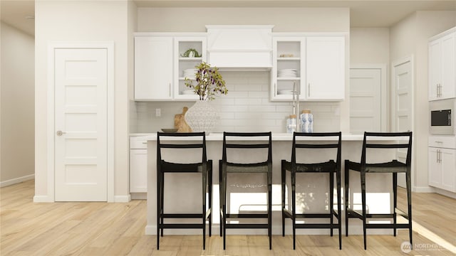 kitchen with a breakfast bar area, light wood-type flooring, white cabinets, and backsplash