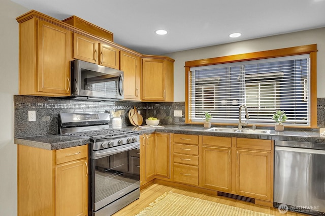 kitchen featuring stainless steel appliances, dark countertops, tasteful backsplash, visible vents, and a sink