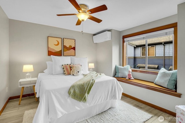 bedroom with ceiling fan, light wood-style flooring, baseboards, and a wall mounted AC