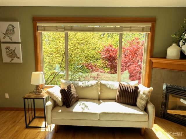 sitting room featuring a tiled fireplace, plenty of natural light, and wood finished floors