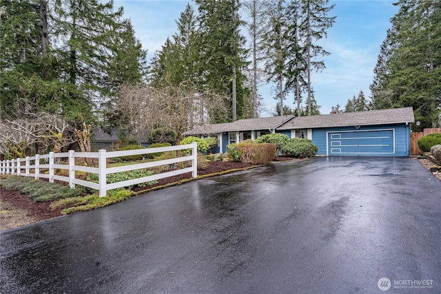 single story home featuring a garage, fence, and aphalt driveway