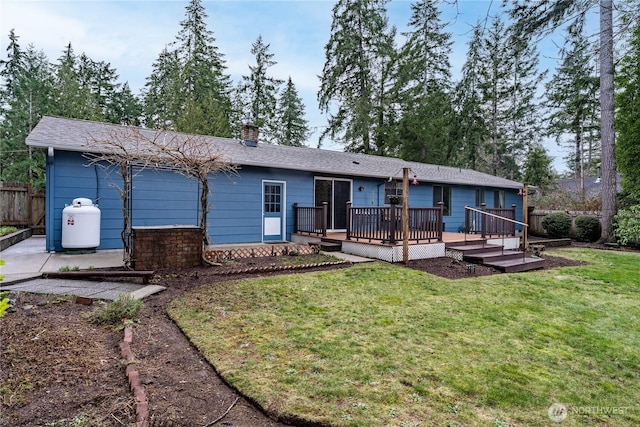 rear view of property featuring a yard, a chimney, fence, and a wooden deck