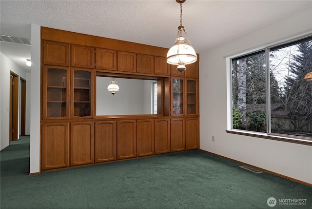 unfurnished dining area with baseboards, visible vents, dark colored carpet, and a textured ceiling