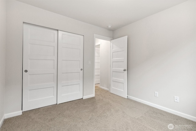 unfurnished bedroom featuring light carpet and a closet