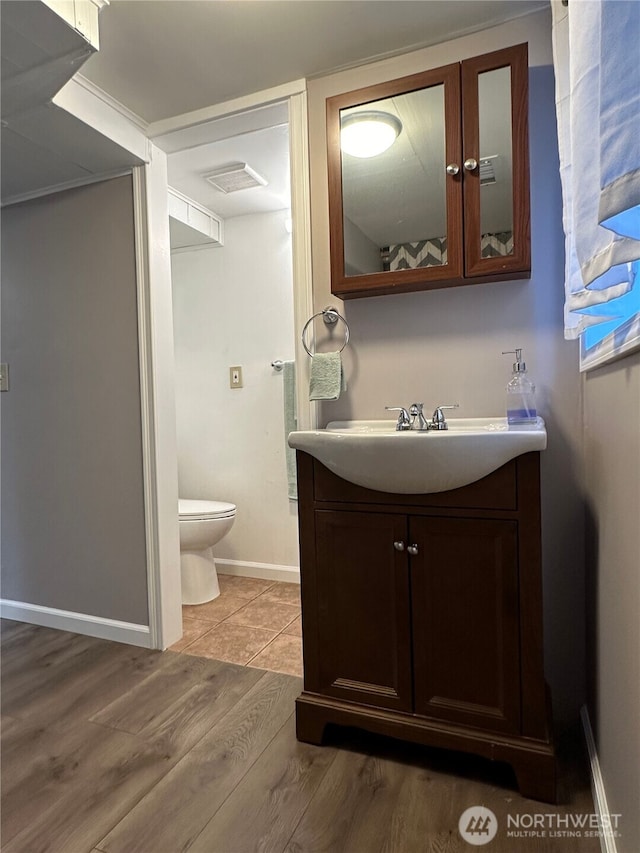 bathroom with toilet, hardwood / wood-style flooring, and vanity