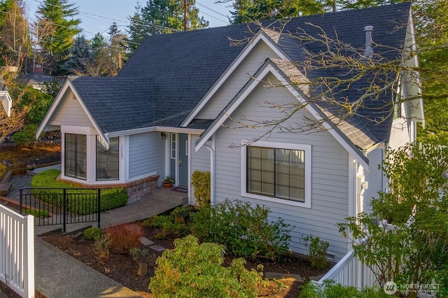 view of front of house with a shingled roof and fence