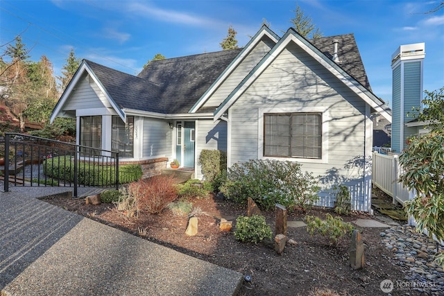 view of front of home featuring a sunroom, a shingled roof, and fence