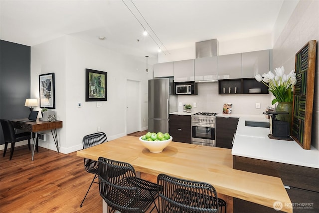 kitchen featuring a peninsula, wood finished floors, a sink, light countertops, and appliances with stainless steel finishes