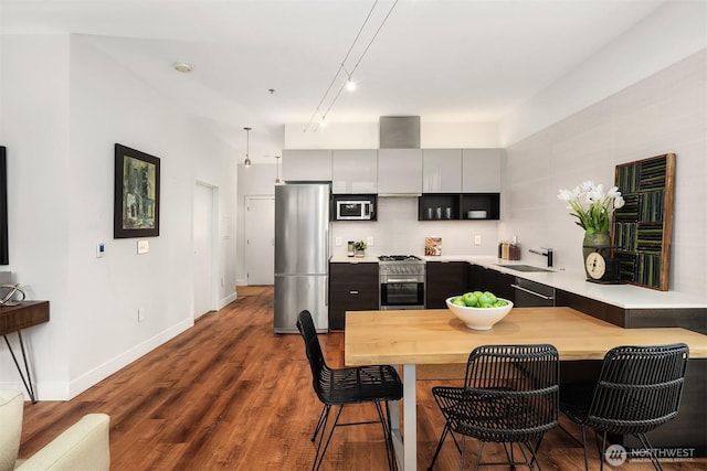 kitchen with a breakfast bar area, dark wood-style flooring, a sink, appliances with stainless steel finishes, and modern cabinets