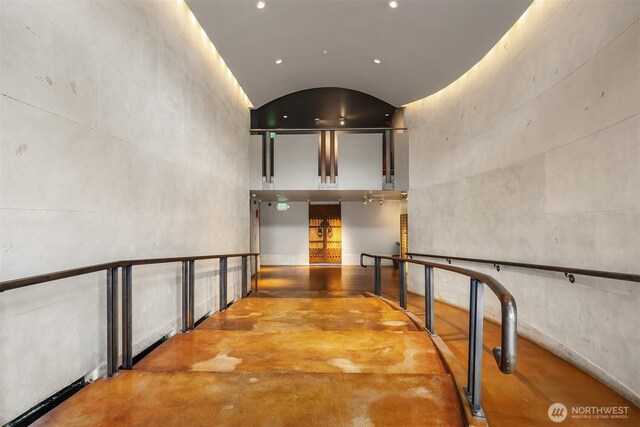 corridor with lofted ceiling and finished concrete floors