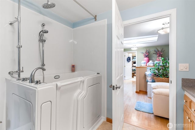 bathroom with hardwood / wood-style flooring, vanity, and a bathing tub