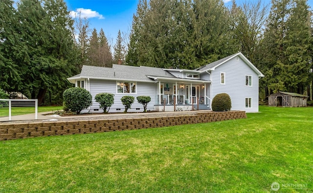 view of front of property featuring covered porch, a front lawn, and a storage shed