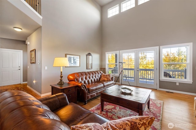 living room with light wood-type flooring, french doors, and a towering ceiling