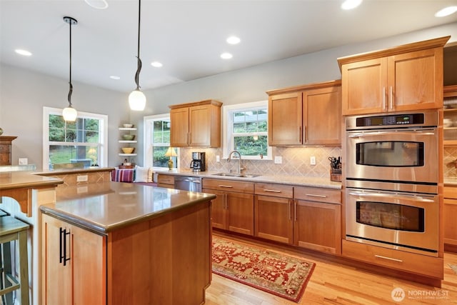 kitchen featuring stainless steel appliances, decorative light fixtures, decorative backsplash, a kitchen island, and sink