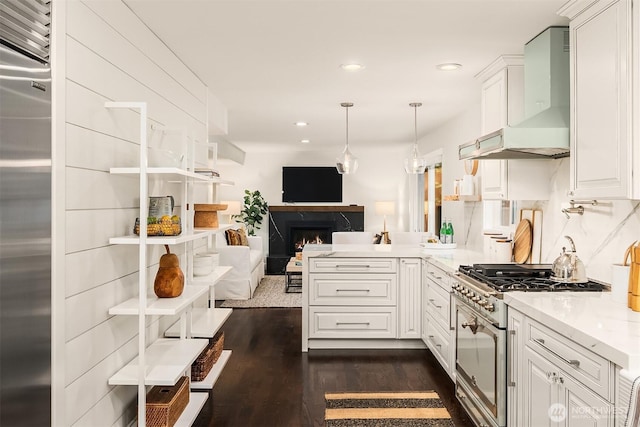 kitchen featuring hanging light fixtures, open floor plan, white cabinets, wall chimney range hood, and high quality appliances