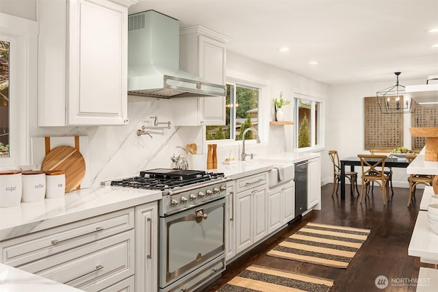 kitchen featuring a sink, white cabinets, decorative backsplash, wall chimney exhaust hood, and range with gas cooktop