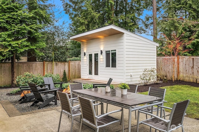 view of patio with a fenced backyard, outdoor dining area, and an outbuilding