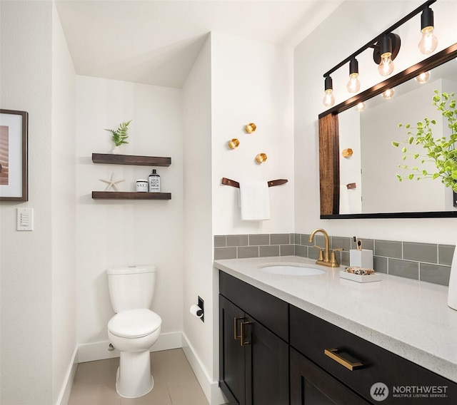 bathroom featuring toilet, baseboards, and vanity