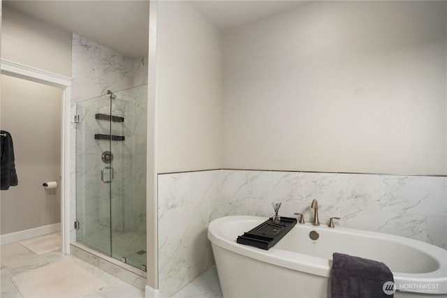 full bathroom featuring marble finish floor, a marble finish shower, and a soaking tub