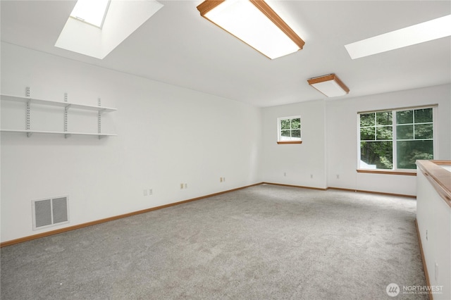 unfurnished room featuring light carpet and a skylight