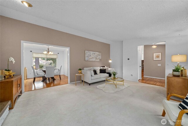 living area with light carpet, a notable chandelier, and a textured ceiling