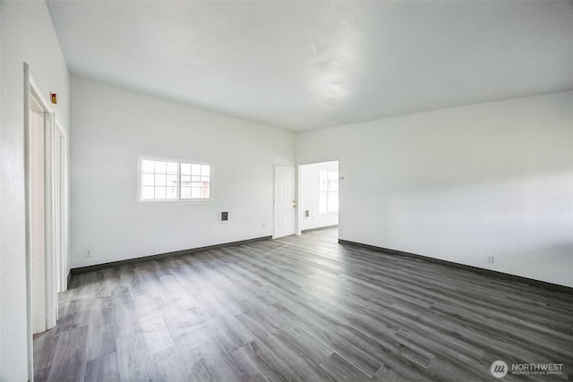 empty room with dark hardwood / wood-style floors and a healthy amount of sunlight