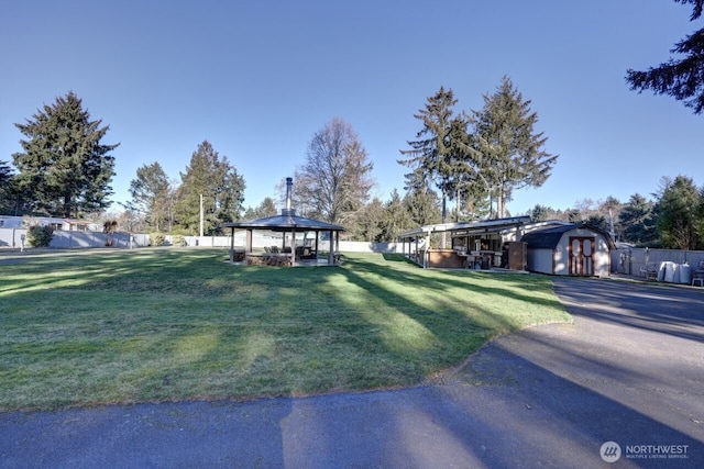 view of front of home featuring a fenced backyard, a gazebo, an outdoor structure, a shed, and a front lawn