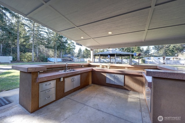 view of patio with exterior kitchen, a sink, a gazebo, and fence