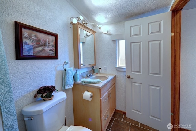 bathroom with a textured ceiling, a textured wall, tile patterned flooring, toilet, and vanity