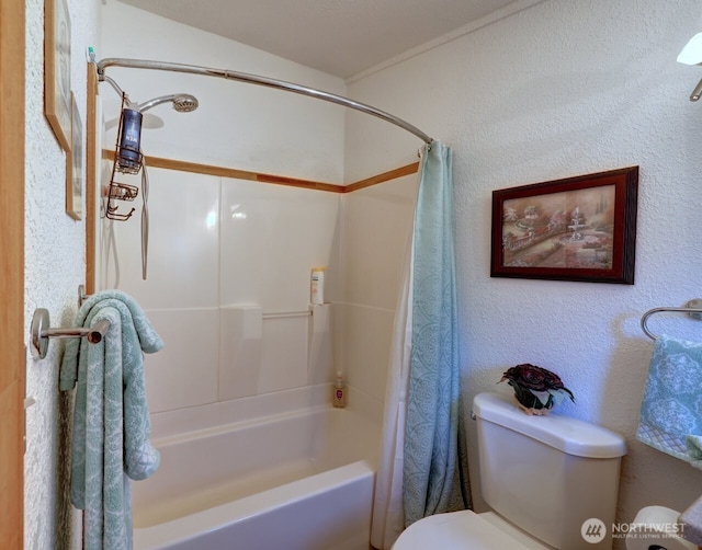 full bathroom featuring toilet, shower / bath combo, and a textured wall