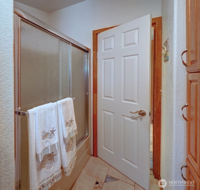 full bath featuring bath / shower combo with glass door and tile patterned floors