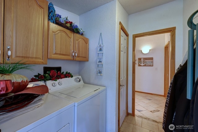 laundry room with light tile patterned floors, a textured ceiling, baseboards, cabinet space, and washer and clothes dryer