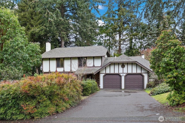 tudor home featuring a garage, aphalt driveway, and a chimney