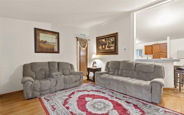 living room with lofted ceiling, light wood finished floors, baseboards, and visible vents