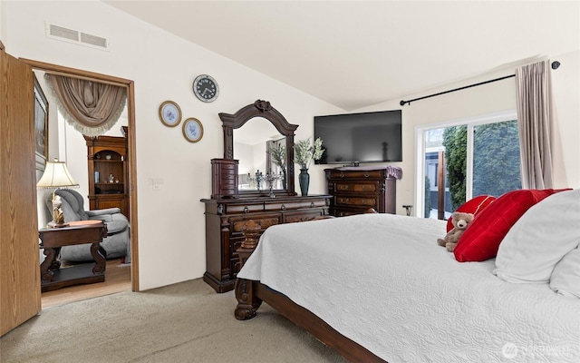 bedroom featuring light colored carpet, lofted ceiling, and visible vents