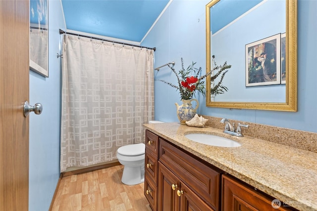 bathroom with crown molding, a shower with shower curtain, toilet, vanity, and wood finished floors