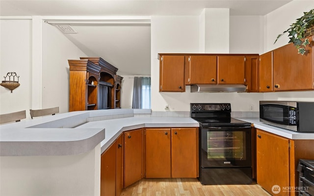 kitchen with light countertops, stainless steel microwave, electric range, ventilation hood, and light wood-type flooring