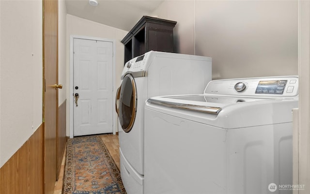 washroom featuring light wood-style flooring, washing machine and clothes dryer, and cabinet space